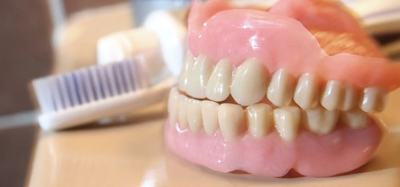 A complete denture resting beside a toothbrush